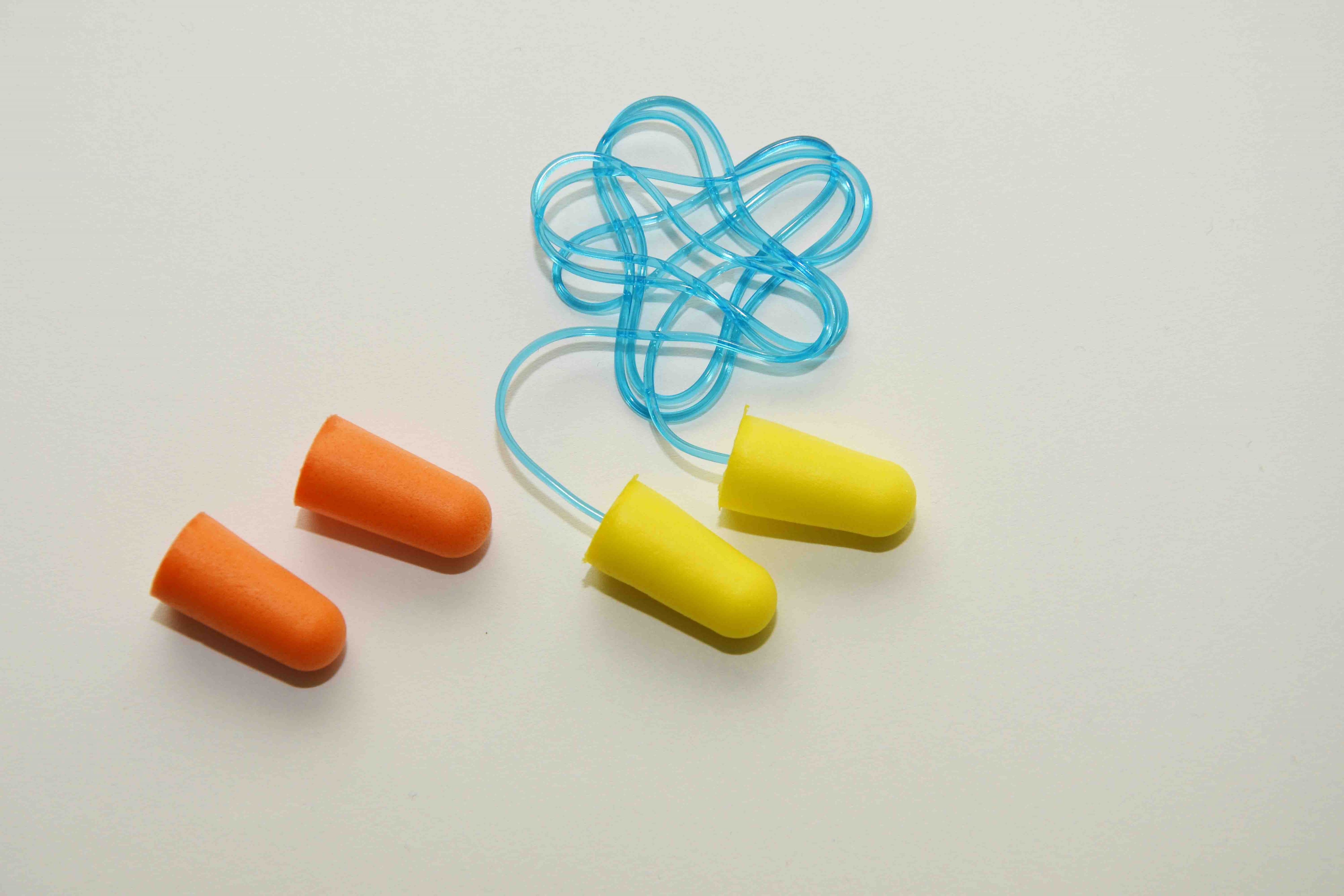 One orange pair of disposable ear plugs and one yellow pair with a blue string